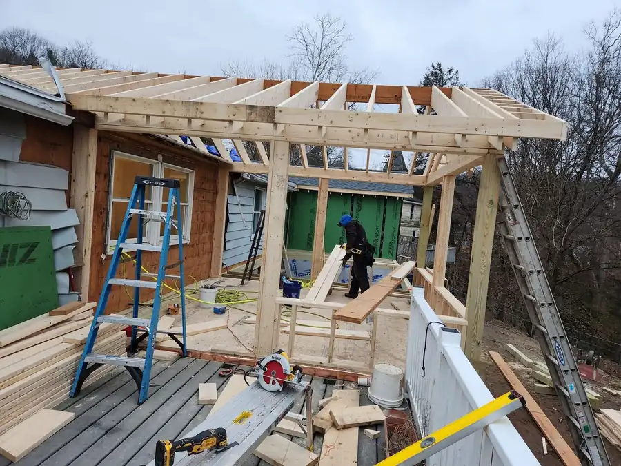 Open-roof addition framed in lumber with a worker on site