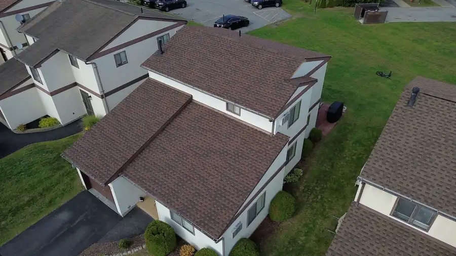 Brown architectural shingles across a row of townhouse roofs from above