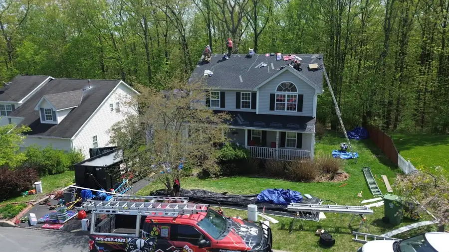 Crew on a two-storey roof with the red company pickup in the drive