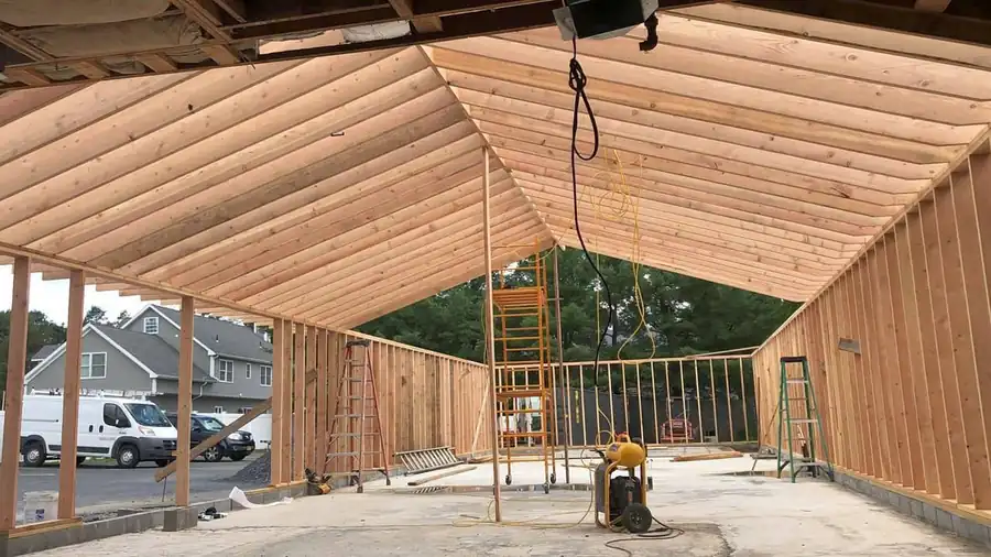 Inside a newly framed gable addition, rafters and studs open to the daylight